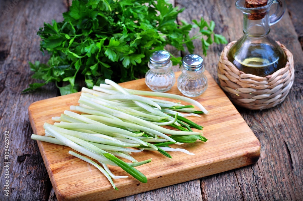 ramson (wild garlic) on a wooden board with parsley and olive oil