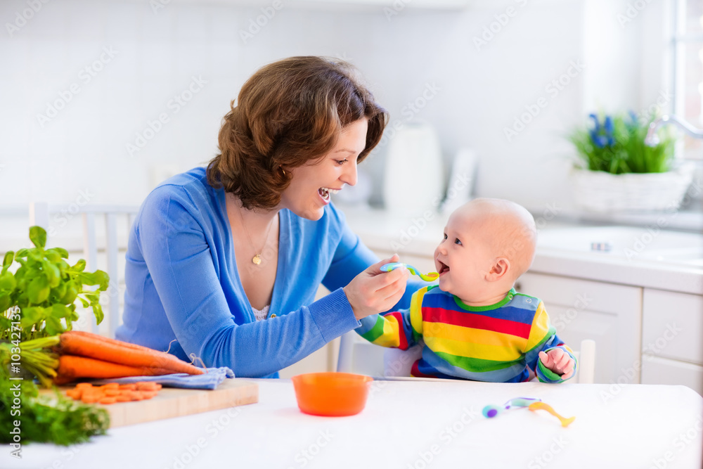 Mother feeding baby first solid food Mother feeding baby first solid food