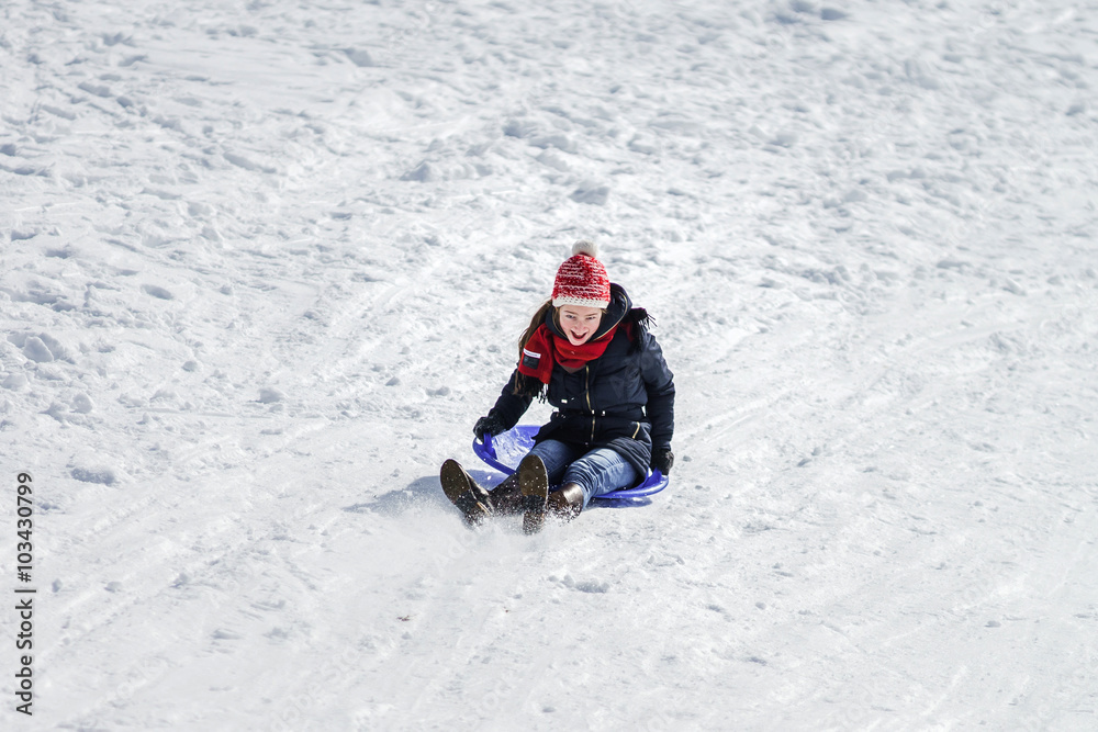 Teenage girl sledding from the hill
