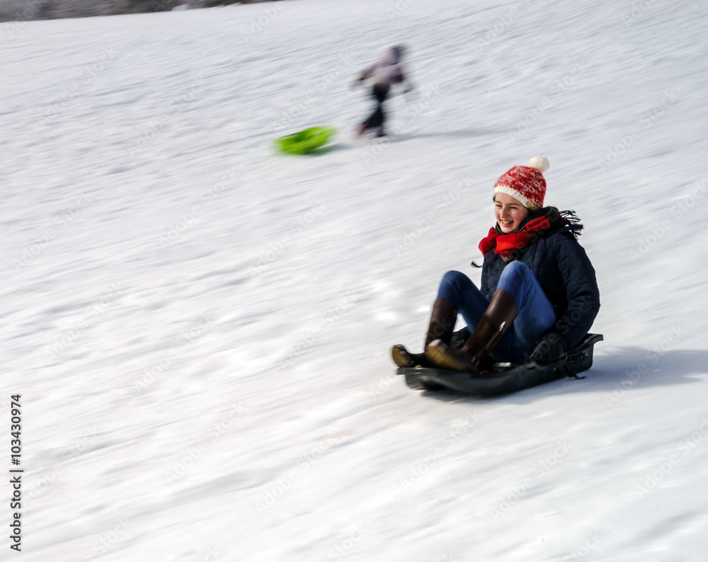 Teenage girl sledding from the hill