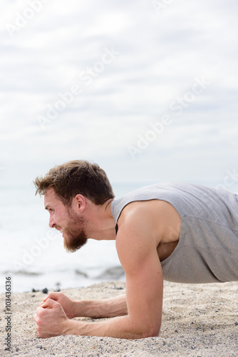 Core body workout fitness man doing plank exercises. working out his midsection muscles. Fit athlete fitness cross training planking exercising outside in summer on beach sand.