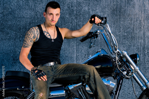 Tough, tattooed fighter with his bike in chopper-style