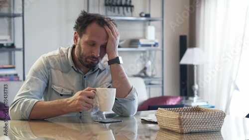 Sleepy man drinking coffee by table in the morning
