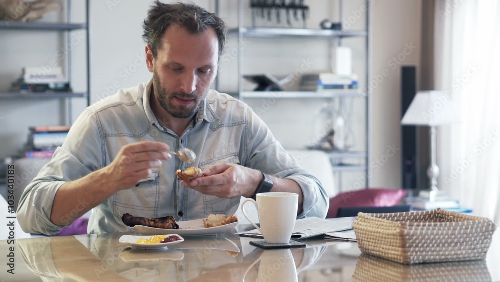 Young man spreading jam during breakfast by dinning table at home
Young man spreading jam during breakfast by dinning table at home