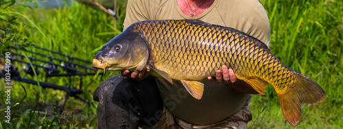 Happy fisherman holding a beautiful common carp