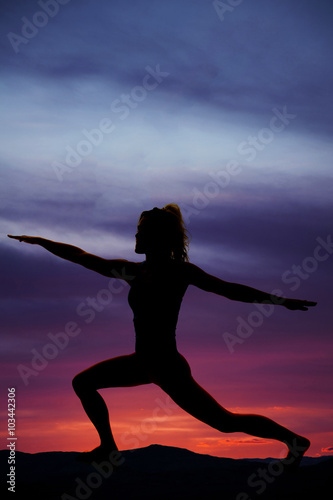 silhouette of a woman in lunge with arms out in sunset