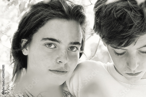 portrait of two teenagers behind some leaves