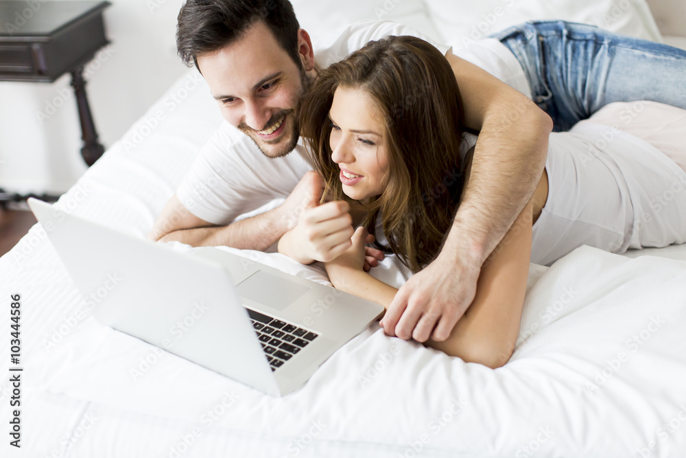 Young couple with laptop in the bed Young couple with laptop in the bed