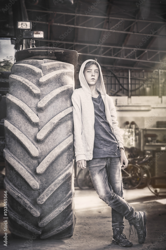 portrait of a teenage boy leaning against a huge tire