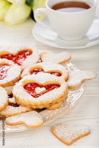 Shortbread cookies in the shape of heart with strawberry jam on wooden table.