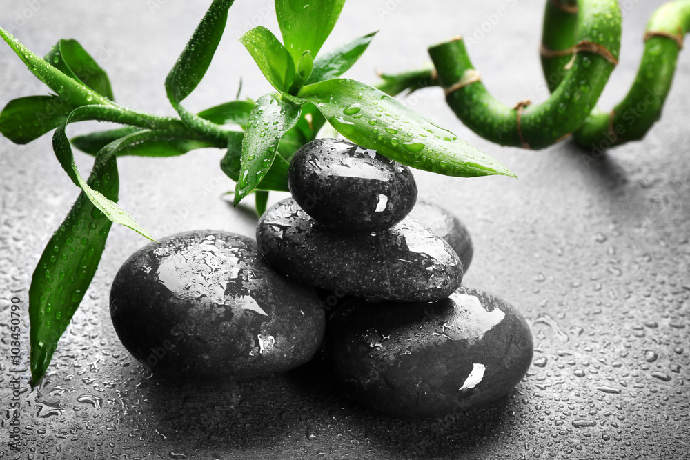 Naklejka premium Hot spa stones with bamboo on grey background, close-up