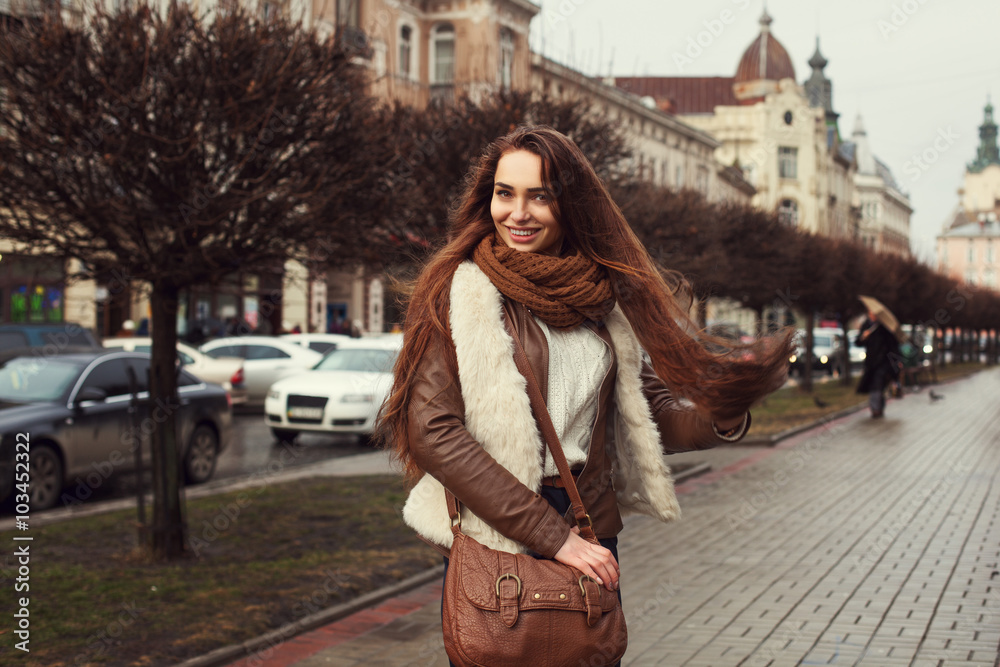 Outdoor portrait of young beautiful smiling lady wearing stylish clothes standing on the street. Model looking at camera. Female fashion concept. 