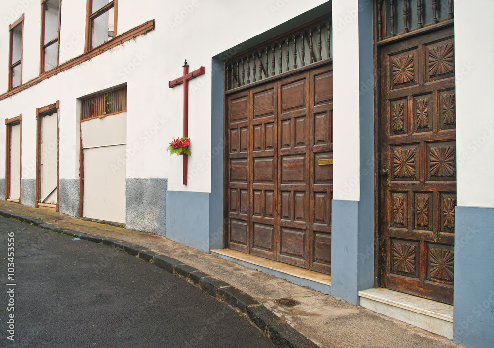 Fototapeta street with big cross on old white building wall
