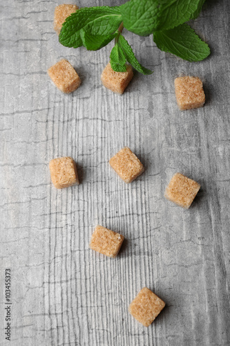 Pile of brown sugar cubes and stevia on grey wooden background