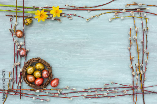 Easter background. Border of willow branch and quail eggs in small nest. Copy space  top view