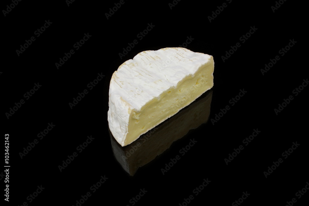 ein stück camembert käse auf schwarzen hintergrund