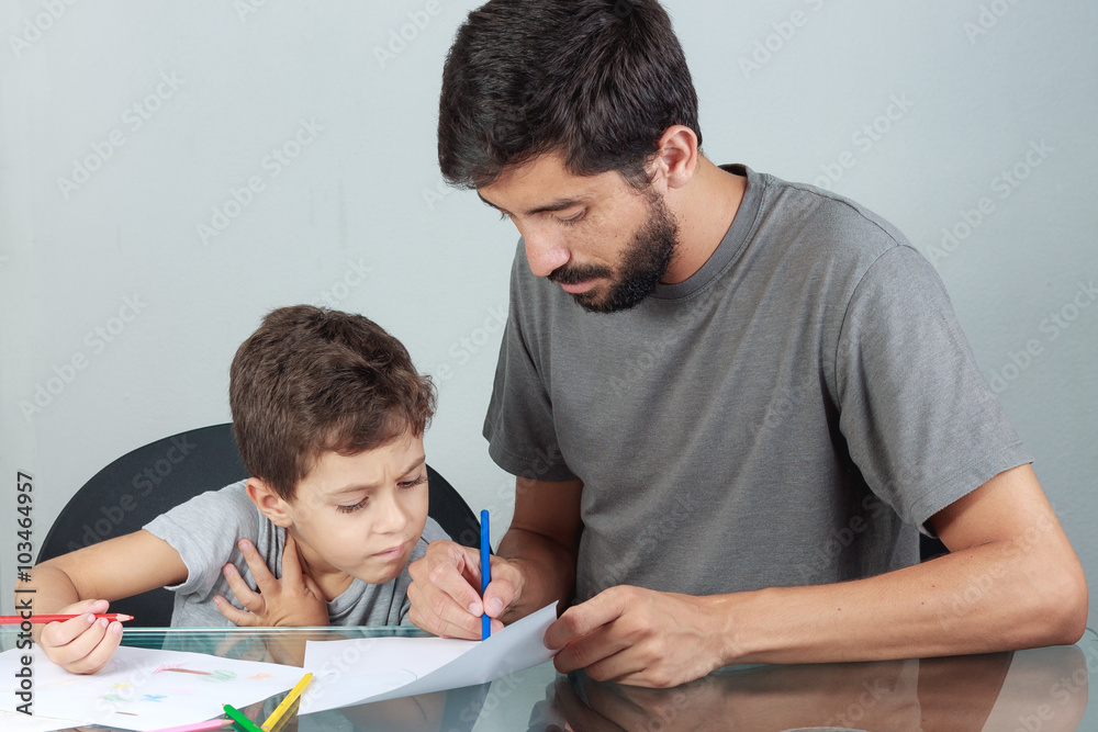 Young father and son drawing with colored pencils on the living Young father and son drawing with colored pencils on the living