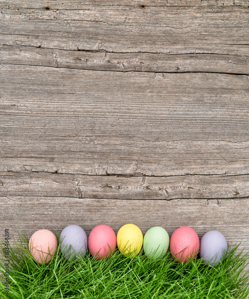 Easter eggs in green grass over wooden background Easter eggs in green grass over wooden background