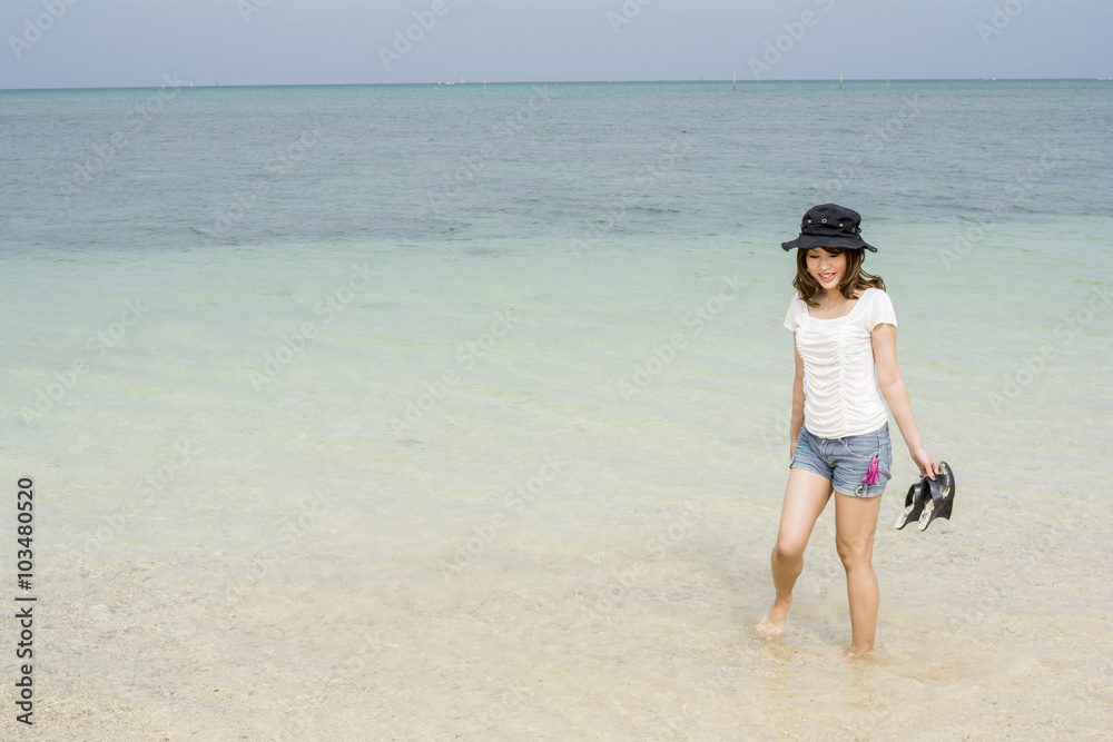 沖縄県恩納村の海辺に立って微笑む女性