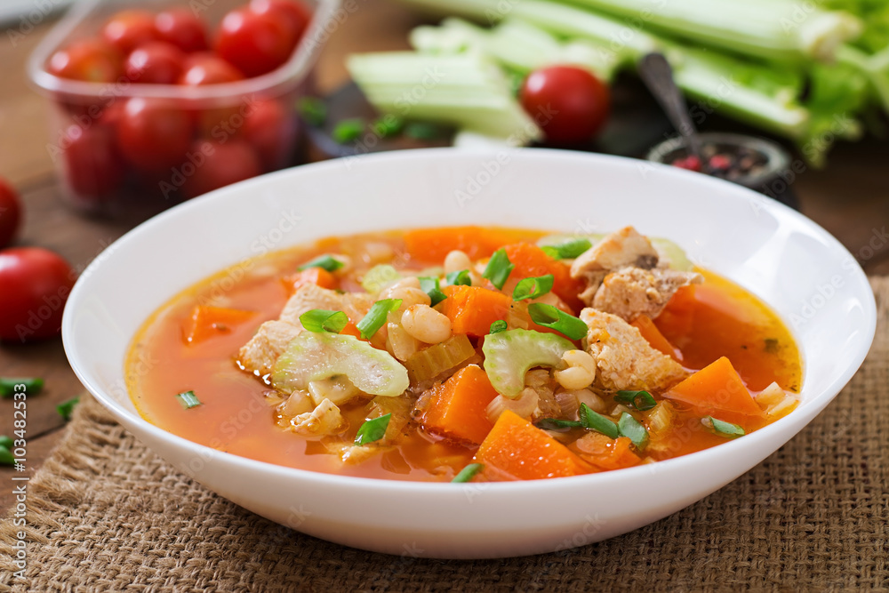 Tomato chicken soup with pumpkin, beans and celery in white bowl Tomato chicken soup with pumpkin, beans and celery in white bowl