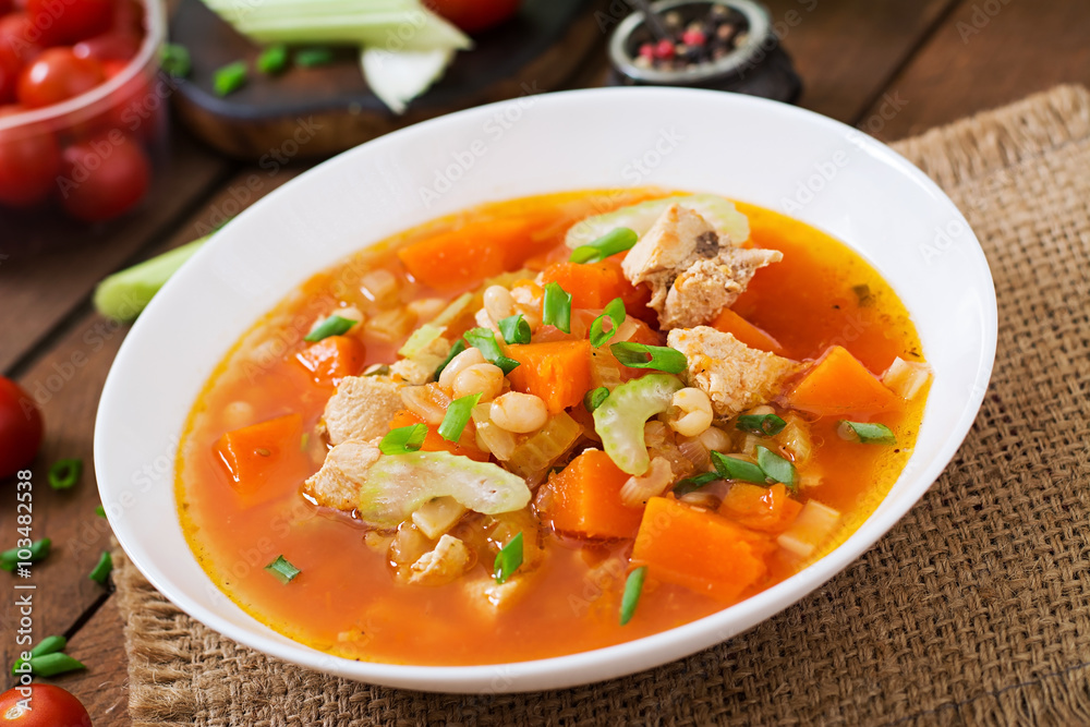 Tomato chicken soup with pumpkin, beans and celery in white bowl Tomato chicken soup with pumpkin, beans and celery in white bowl