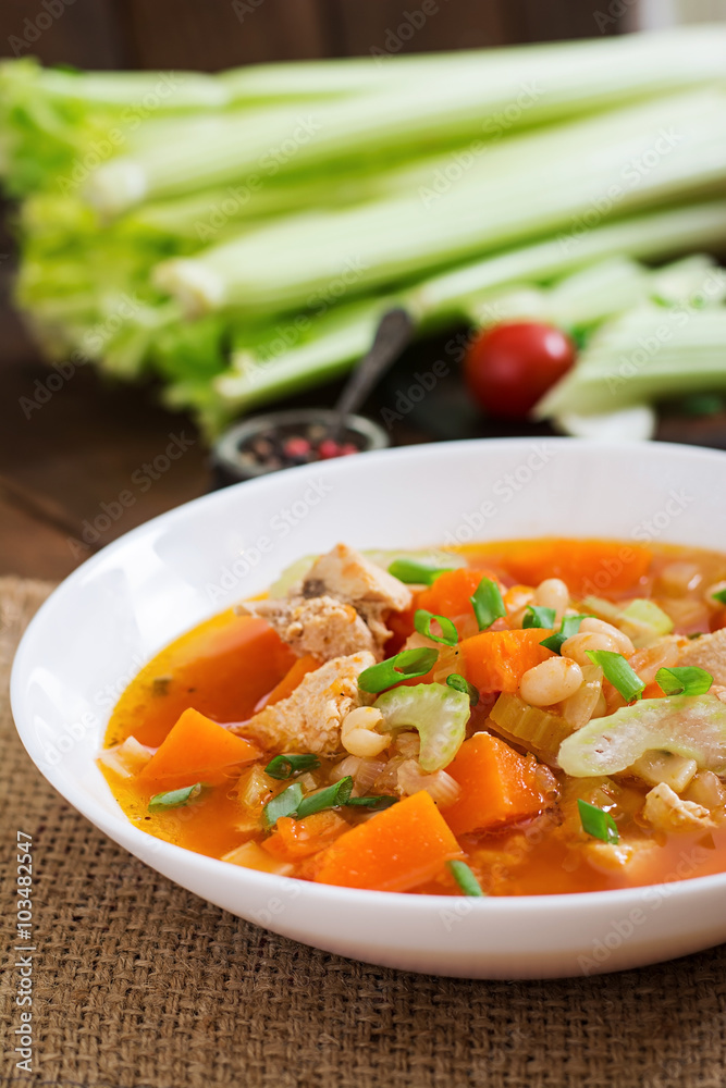 Tomato chicken soup with pumpkin, beans and celery in white bowl Tomato chicken soup with pumpkin, beans and celery in white bowl