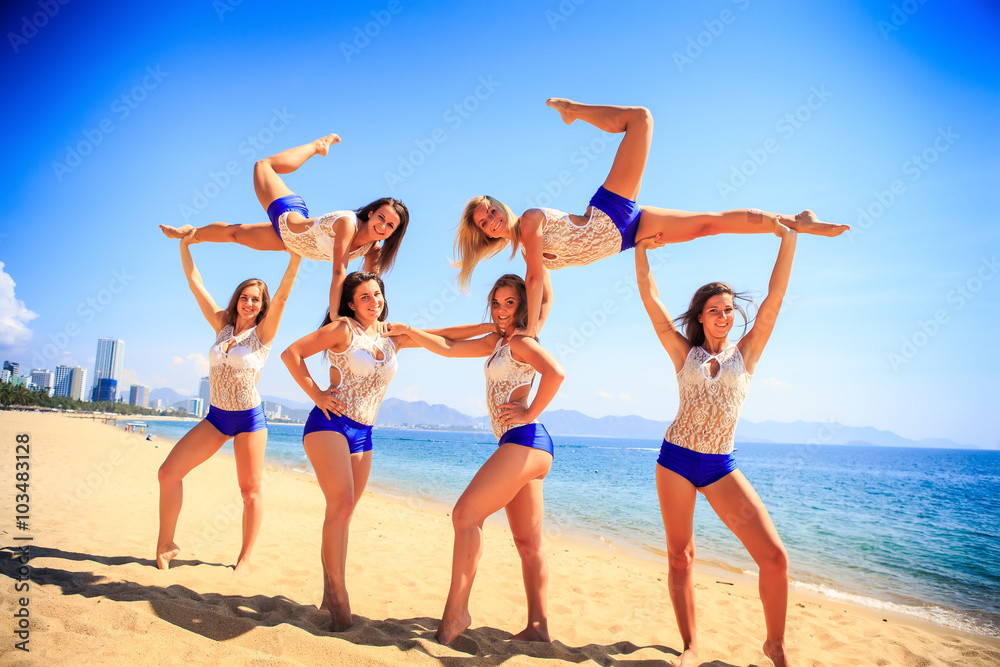 cheerleaders perform sideview Swedish falls on beach against sea