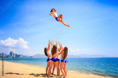 cheerleaders performs stunt Basket Toss on beach against resort
