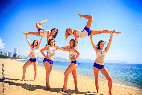 cheerleaders perform sideview Swedish falls on beach against sea