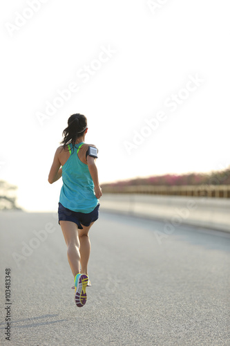 young woman runner running on city road