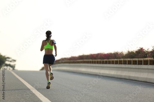 young woman runner running on city road