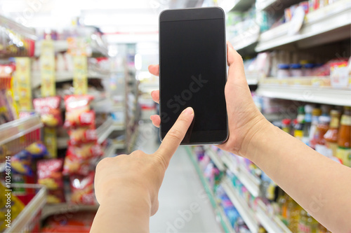 Hand holding smartphone at at convenience store