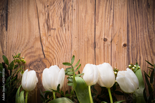 White tulips and greenery on wooden board photo