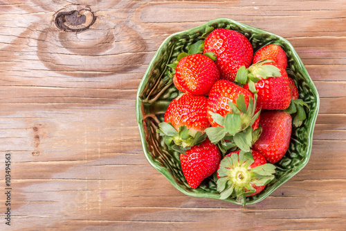 strawberries in a wooden bowl on the old wooden table
