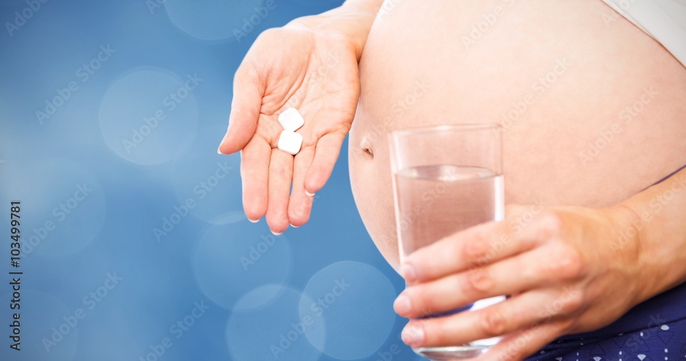 Composite image of pregnant woman taking a vitamin tablet Composite image of pregnant woman taking a vitamin tablet