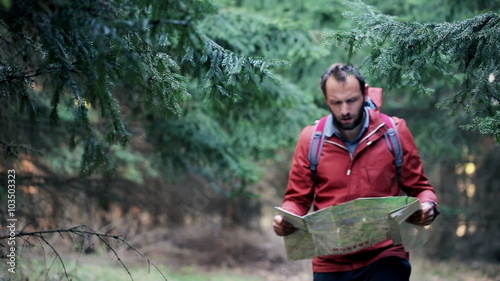 Young, lost man with a map looking for direction in forest
 photo