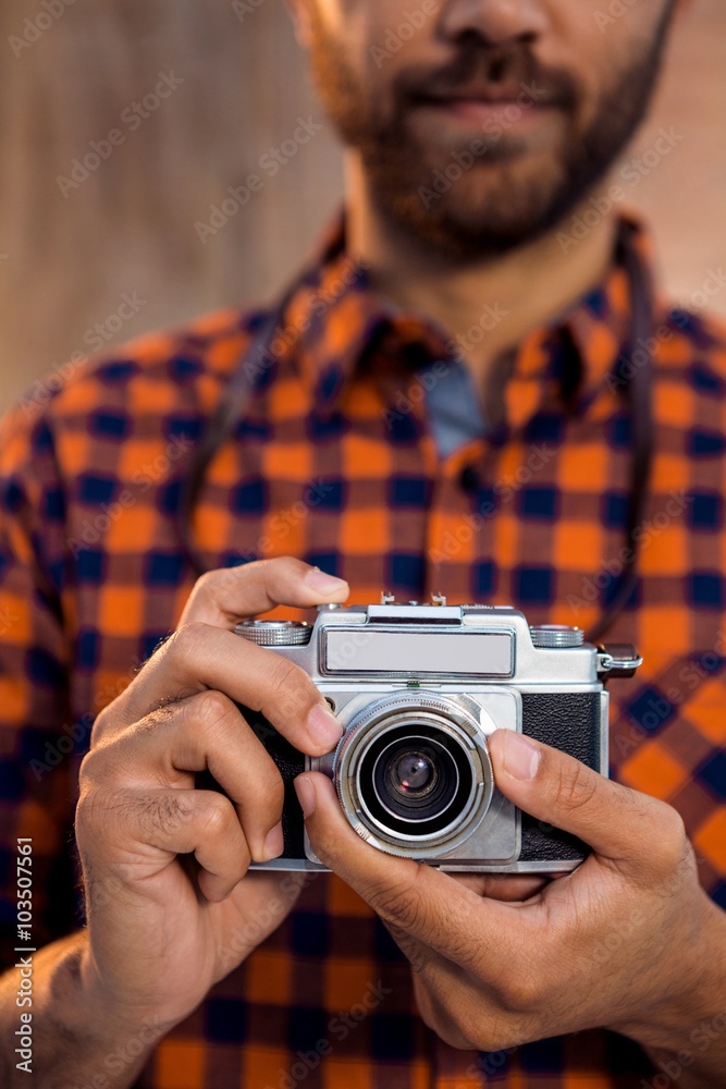 Mid section of businessman holding camera against wall in office Mid section of businessman holding camera against wall in office