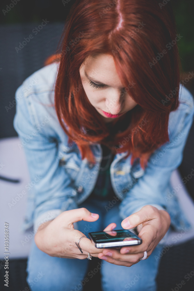Young handsome caucasian redhead woman holding a smartphone look Young handsome caucasian redhead woman holding a smartphone look