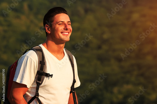 Cose up of smiling man with backpack on nature backgound