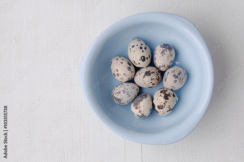 Blue bowl with fresh quail eggs on white wooden background Blue bowl with fresh quail eggs on white wooden background