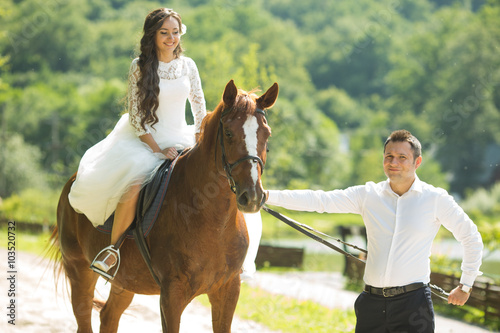 stylish gorgeous happy brunette bride riding a horse and elegant