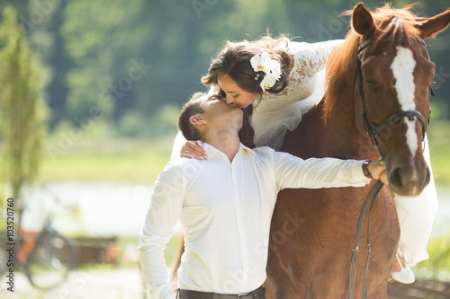 stylish gorgeous happy brunette bride riding a horse and kissing