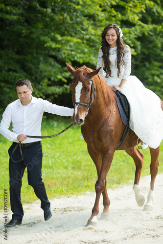 stylish gorgeous happy brunette bride riding a horse and elegant