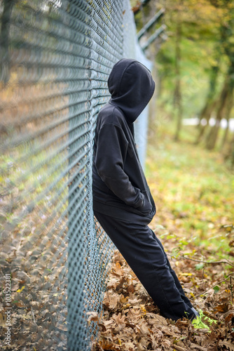 wire fence standing in front of hooded young photo