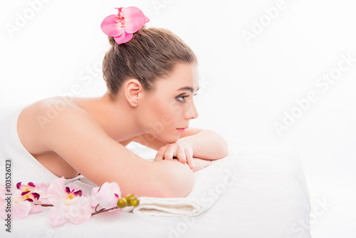 Pretty young girl lying in sauna and relaxing with orchid, side