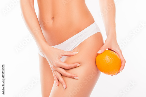 No to cellulite! Woman in white panties holding orange near hip