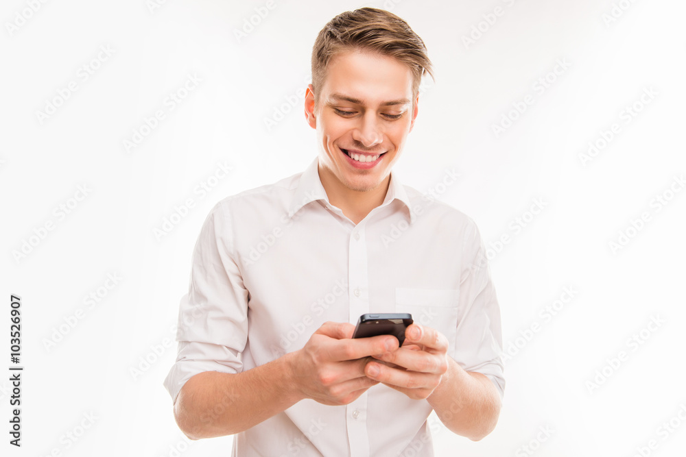 Young cheerful businessman typing sms on his smartphone Young cheerful businessman typing sms on his smartphone
