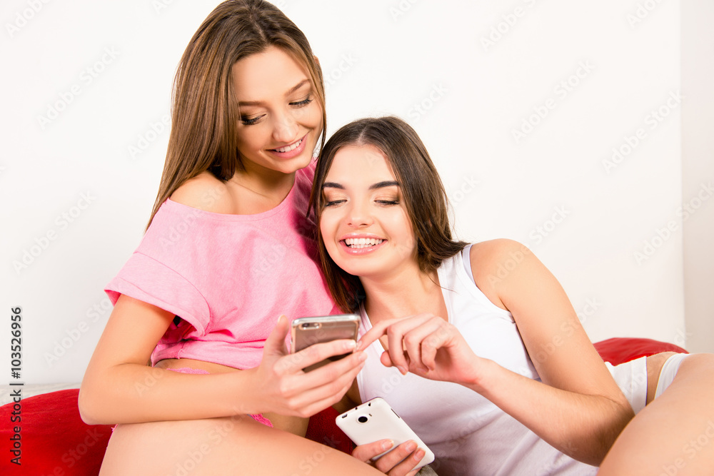 Smiling girl showing to her sister message on her phone Smiling girl showing to her sister message on her phone
