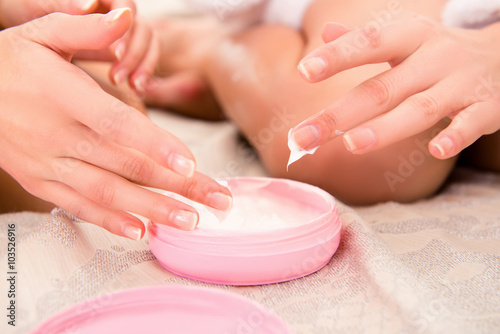 Close up photo of two young girls smearing cream on their hands