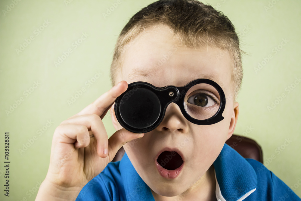 boy looking through a magnifying glass and is surprised boy looking through a magnifying glass and is surprised